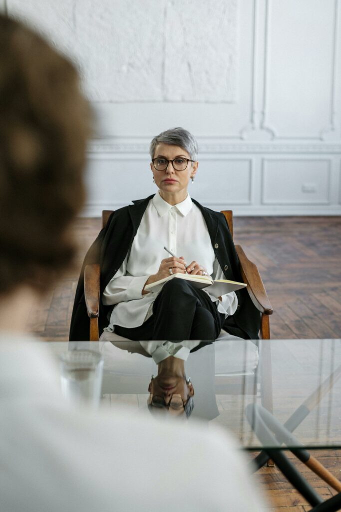 A professional therapist conducts a counseling session in a modern, minimalist office setting.